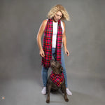 A person standing with a black dog in front of them, both wearing matching pink plaid scarves.