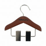 A wooden clothes hanger with a brown finish and silver metal clips and hook, featuring the brand name 'TINKA & Co.' printed on the front, set against a textured white background.