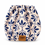 A reusable cloth diaper with a navy blue floral pattern on a cream background, featuring a brown leather TINKA & Co brand patch at the bottom center.
