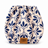 A reusable cloth diaper with a navy blue floral pattern on a cream background, featuring a brown leather TINKA & Co brand patch at the bottom center.