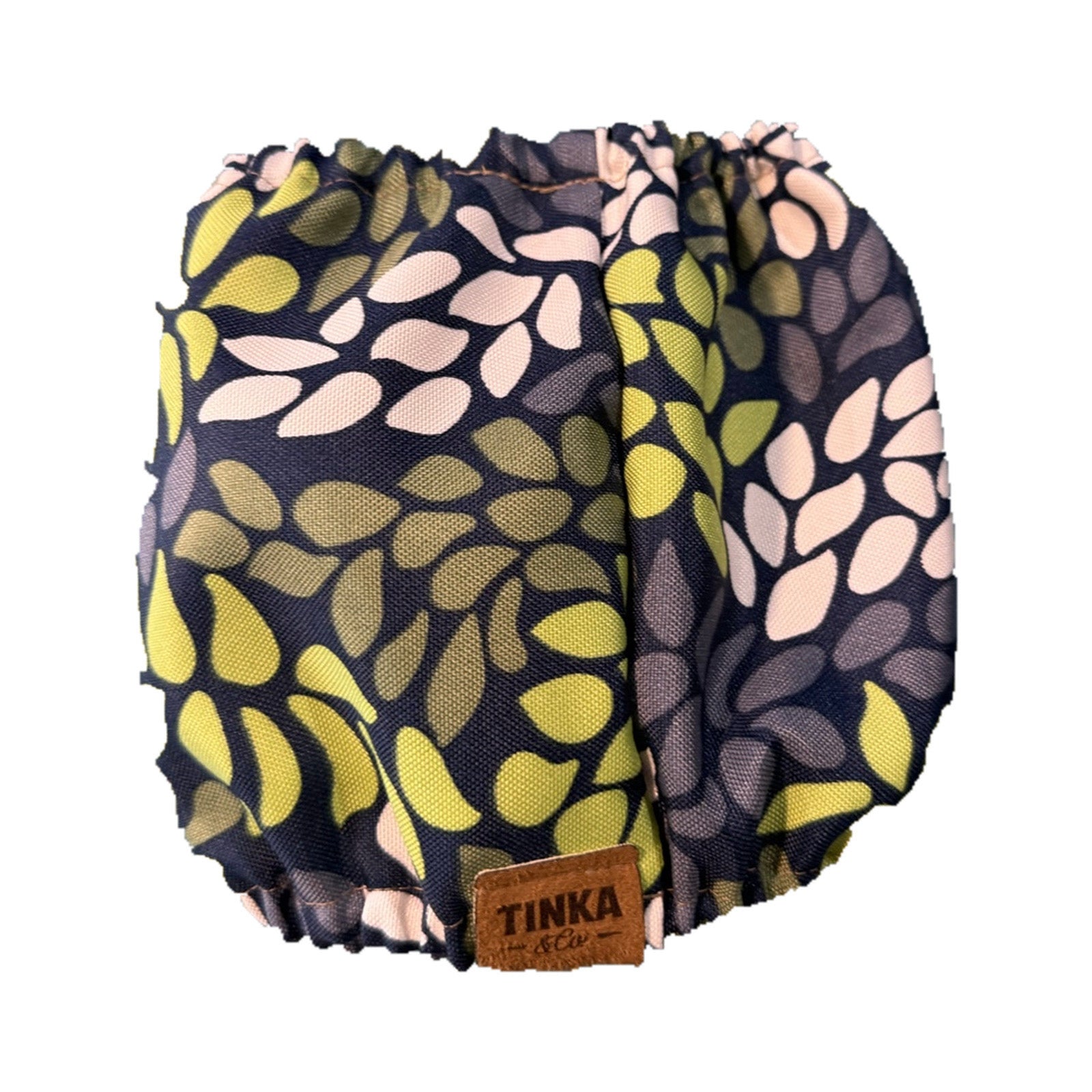 A pair of ruffled bloomers with a navy blue background and a retro leaf pattern in olive green, light pink, and gray. A brown leather patch on the front reads 'TINKA & CO'